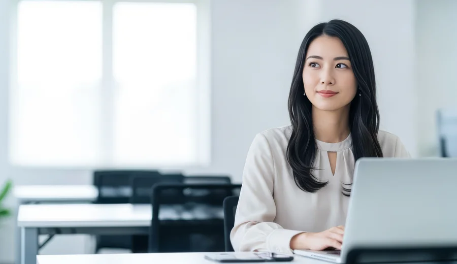 明るいオフィスでノートパソコンに向かうキャリア女性